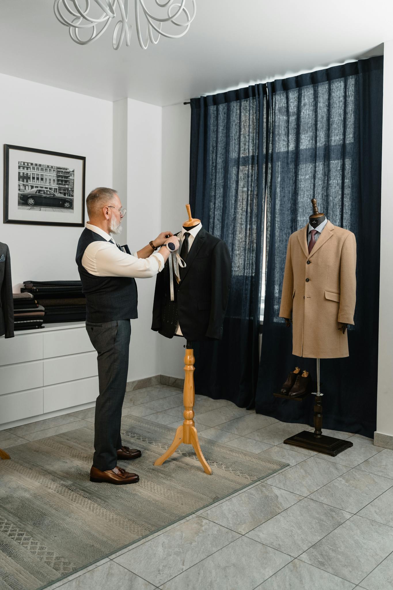 A professional tailor adjusting a suit on a mannequin in a stylish workshop setting.
