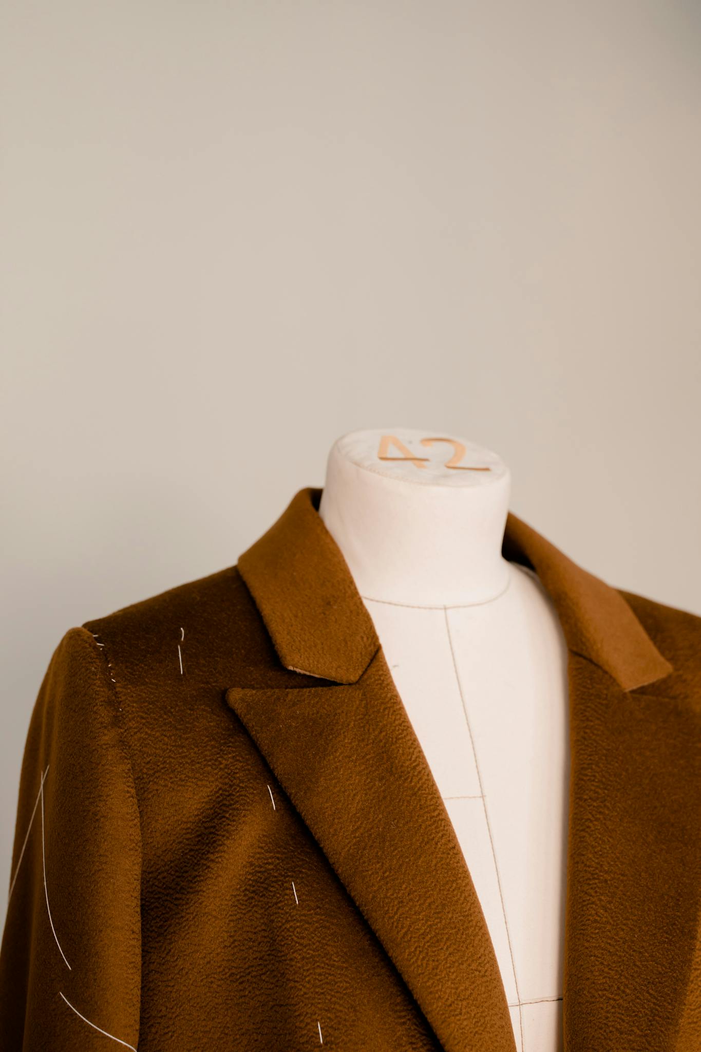 Close-up view of a brown blazer on a mannequin showcasing tailoring design and fabric.