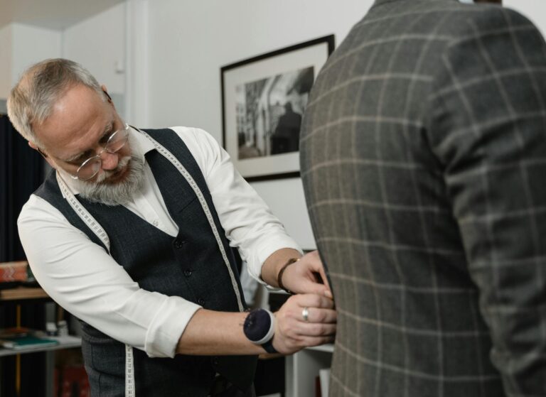 Experienced tailor meticulously adjusting a client's suit jacket in a professional setting.