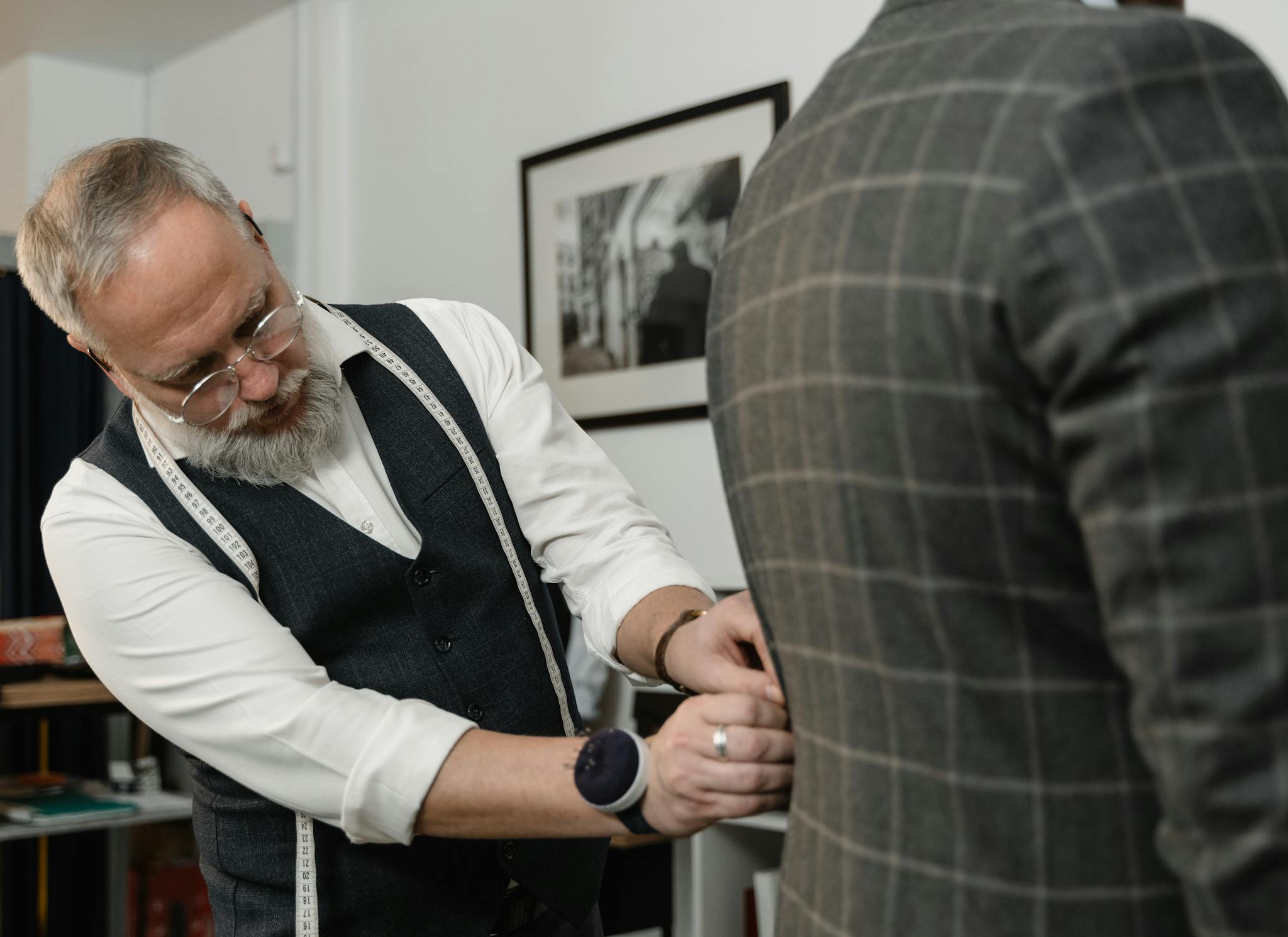 Experienced tailor meticulously adjusting a client's suit jacket in a professional setting.