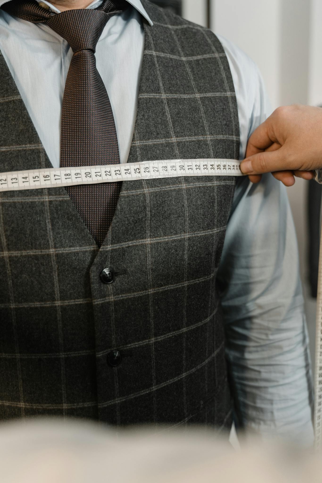 Tailor measuring client's chest for a tailored suit in an atelier setting.